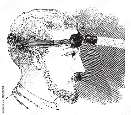 Man with electric light attached to strap on forehead, vintage e