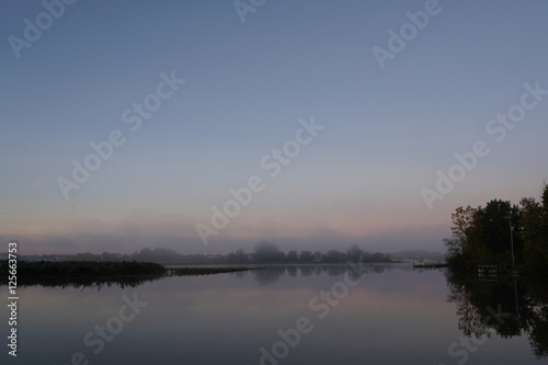 Fototapeta Naklejka Na Ścianę i Meble -  Fog over calm river on cold October morning
