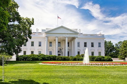 The White House on a summer day with the American flying over it.
