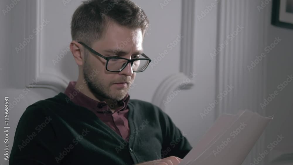 Cheerful businessman with glasses in the office receiving news, he is holding a contract document Cheerful businessman with glasses in the office receiving news, he is holding a contract document
