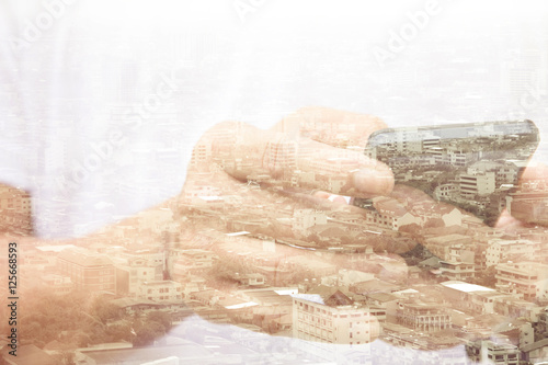  Double exposure of using smart phone and cityscape background ,Business technology concept. 
