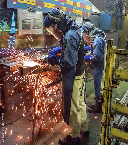 The worker grinding metal in manufacturing plant
