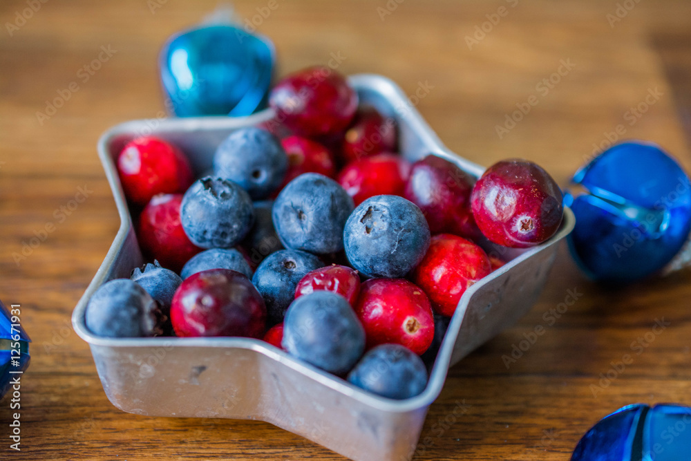 Cranberries and blueberries on plate in the form of stars. Blue Christmas balls on the Christmas tree Cranberries and blueberries on plate in the form of stars. Blue Christmas balls on the Christmas tree