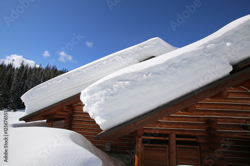 Huge amount of snow on the roof of a Montana cabin with blue sky