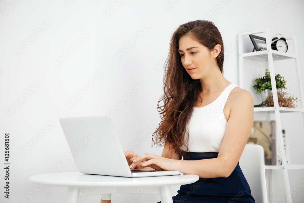 Beautiful Caucasian woman working on laptop on white desk over white isolated background with copy space Beautiful Caucasian woman working on laptop on white desk over white isolated background with copy space