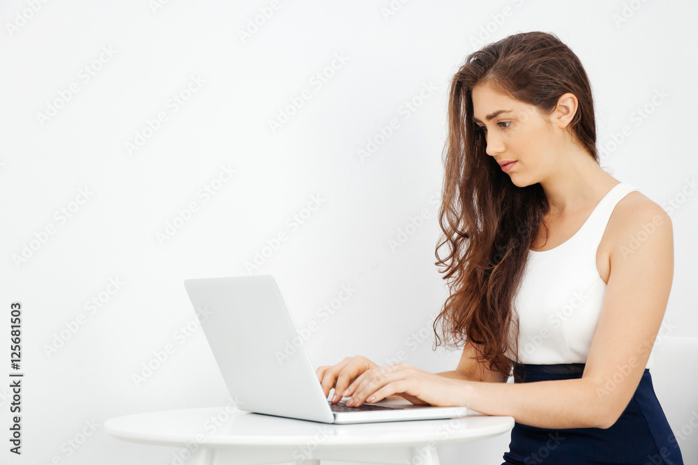 Beautiful Caucasian woman working on laptop on white desk over white isolated background with copy space Beautiful Caucasian woman working on laptop on white desk over white isolated background with copy space