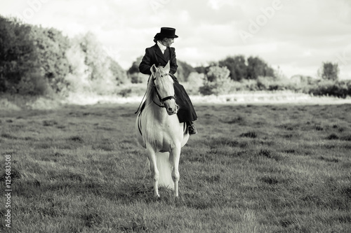 Lady rider in side saddle on white horse photo
