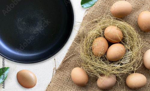 cooking concept. pan and eggs on burlap with old wood. over light