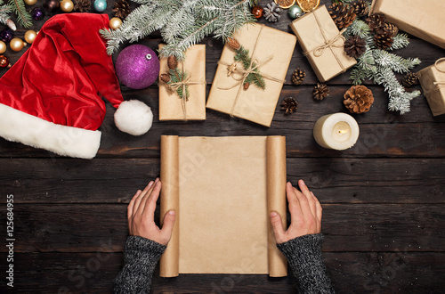 Mens hands holding blank sheet of paper with Christmas gifts