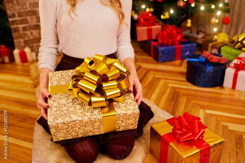 Close-up of girl holding her hands a big box with a big golden b
