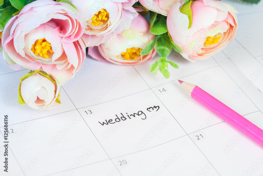word wedding on calendar with sweet flowers and pen 