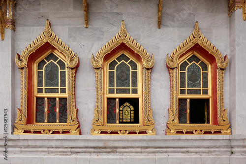 WINDOWS OF THAI TEMPLEThree windows of the thai temple placed repeatedly. They are decorated with low relief and colored with gold color. © commonthings