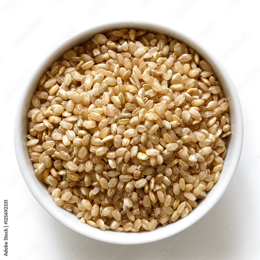 Bowl of short grain brown rice isolated on white from above.