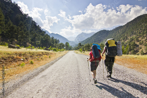 two hikers in turkey mountains walking on road with backpacks
