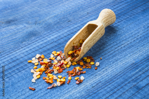 chilli powder with wooden spoon on blue wooden table
