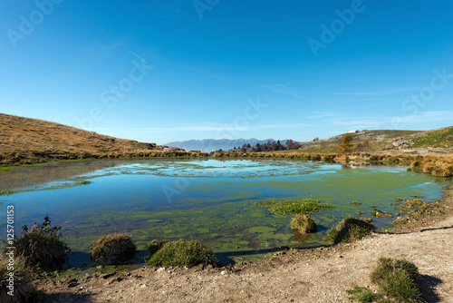 Pond in the plateau of Lessinia with the Alps (Monte Baldo). Verona, Veneto, Italy