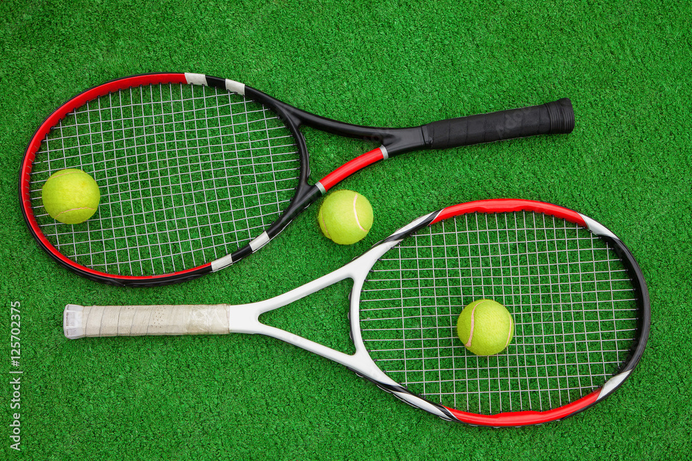 two tennis rackets with three balls on a green background