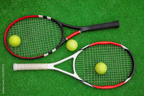 two tennis rackets with three balls on a green background © borisblik