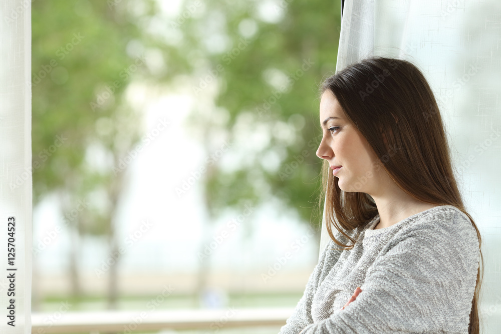 Longing woman looking through window at home Longing woman looking through window at home