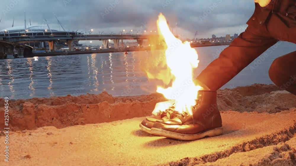 Hand of young man Igniting boots near the waterfront