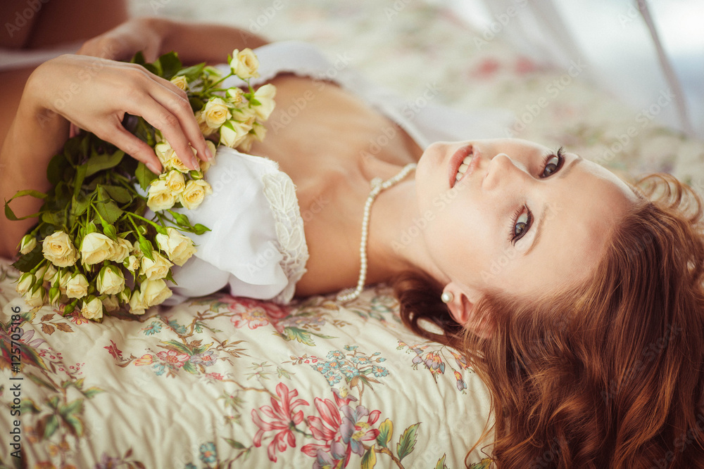 Naklejka premium beautiful and gentle woman lying on the bed with flowers