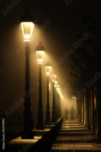 Foto couple walking on dark street illuminated with streetlamps