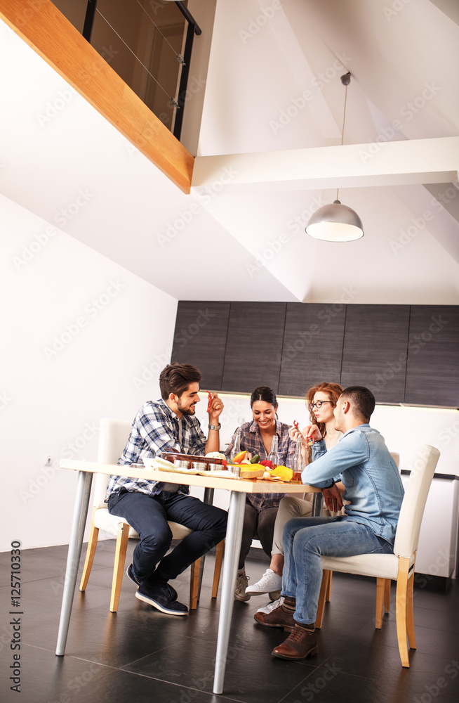 Fototapeta premium Young group of friends in kitchen preparing together vegetarian meal.Cutting vegetables.