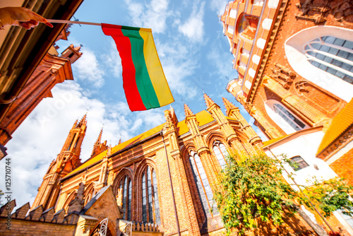 View on the beautiful gothic saint Anna and Francis of Assisi churches eith lithuanian flag in the old town of Vilnius city, Lithuania.
