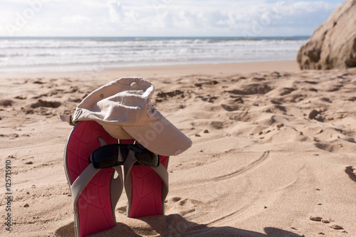 Pair flip flops with sunglasses in the sand of beach, Travel background