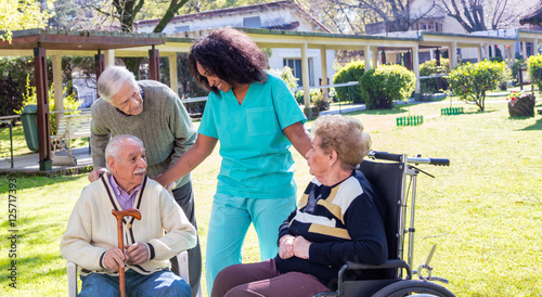 Bild auf Leinwand Afroamerican nurse joking with elder disabled people outdoor