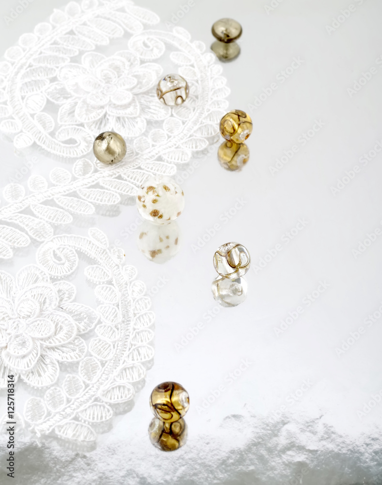 Shimmering glass beads and vintage lace on mirror background
