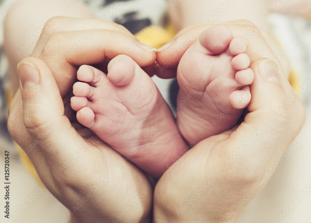 Baby feet in mother hands. Feet on female heart shaped hands closeup. Happy family concept. Mom and her child. Baby feet in mother hands. Feet on female heart shaped hands closeup. Happy family concept. Mom and her child.