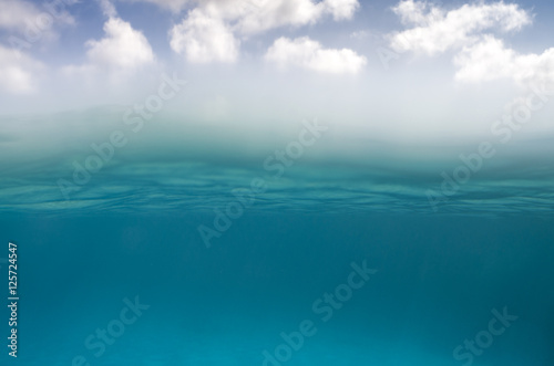 Underwater scene in the bottom and sky with clouds on the top