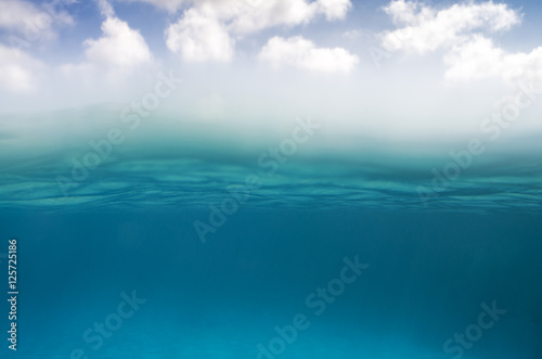 Underwater scene in the bottom and sky with clouds on the top