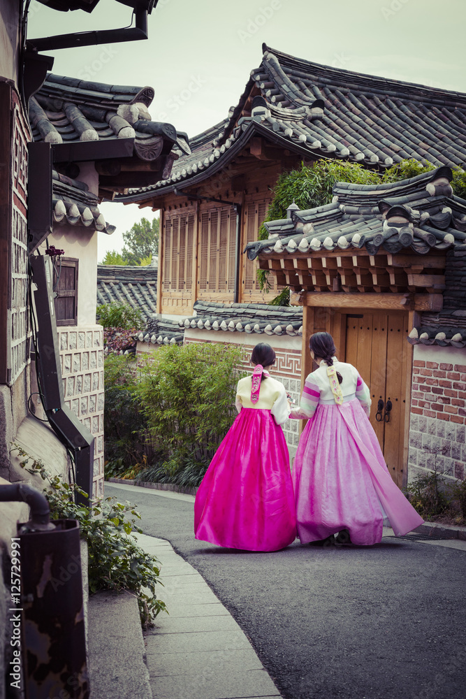 Naklejka premium Kilka kobiet spaceruje po tradycyjnych domach w wiosce Bukchon Hanok w Seulu w Korei Południowej.