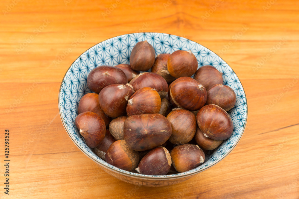 Obraz premium Spanish Chestnuts in a vintage dish on wooden plate background