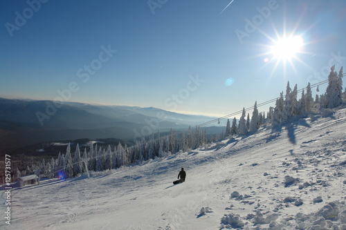 Vászonkép Lonely Snowboarder on the white piste with sun reflections and ski lift and beau