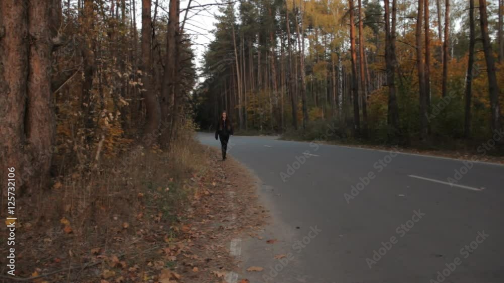 A girl walking along the roadside. And getting out of the frame. A girl walking along the roadside. And getting out of the frame.