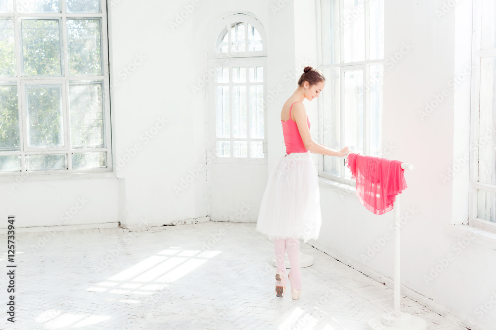 Ballerina posing in pointe shoes at white wooden pavilion Ballerina posing in pointe shoes at white wooden pavilion