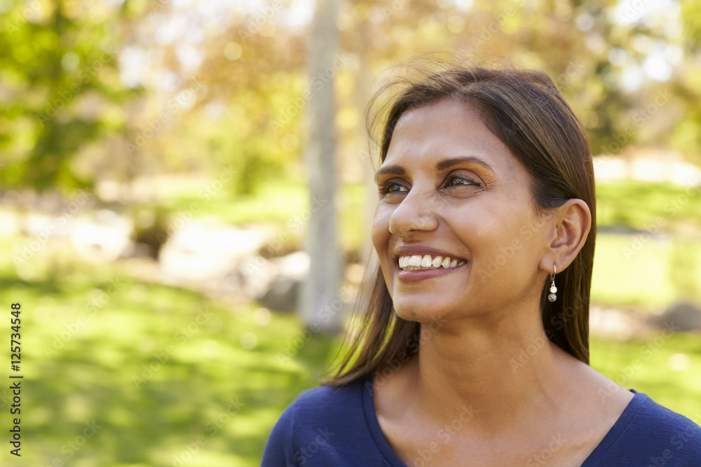 Smiling mixed race woman in park looking away from camera Smiling mixed race woman in park looking away from camera