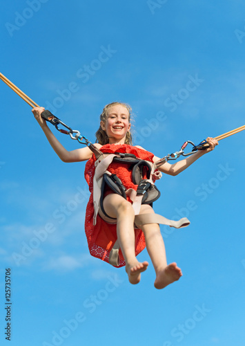 Little girl on bungee trampoline with cords. Place for text.