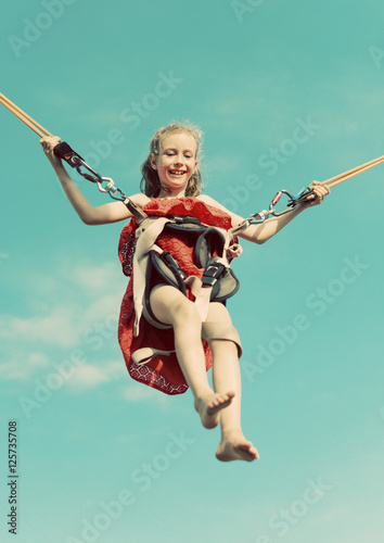 Canvas Print Little girl on bungee trampoline with cords. Place for text.