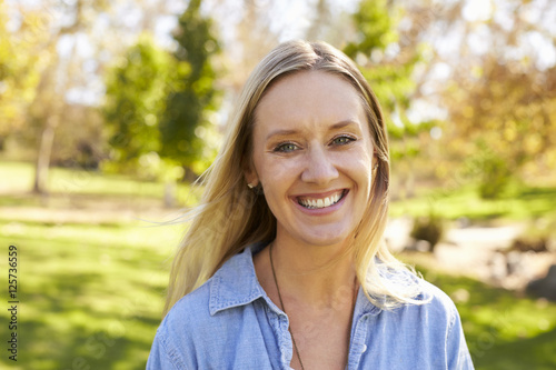 Mid thirties white woman smiling to camera in a park Stock Photo