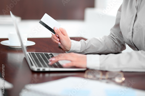 Close up of business woman hands using credit card and laptop computer