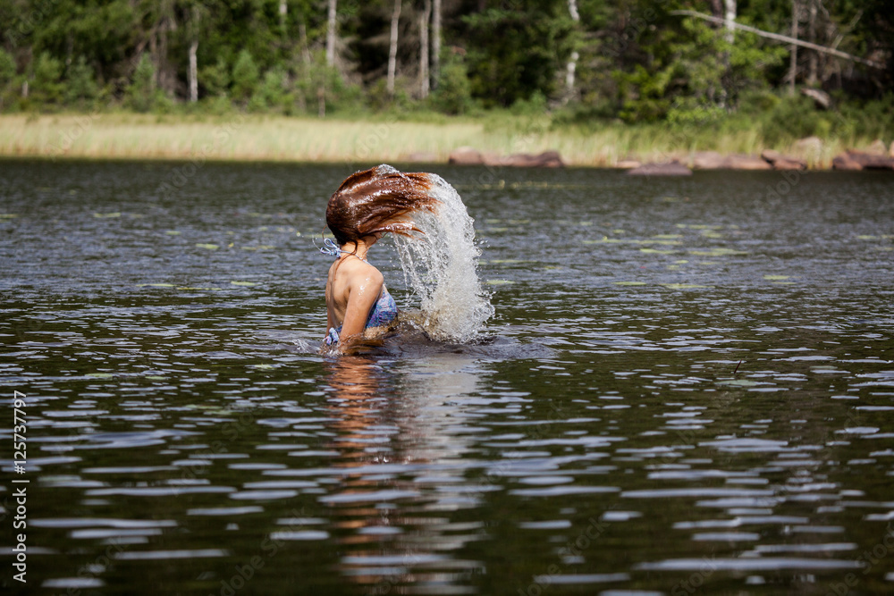 Fototapeta premium Beautiful girl splashing her hear in an Swedish forest lake