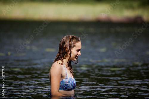 Girl preparing to dive in a Swedish lake surrounded by dense pin