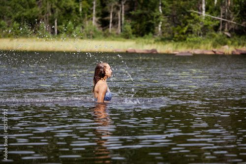 Fototapeta Naklejka Na Ścianę i Meble -  Beautiful girl splashing her hear in an Swedish forest lake