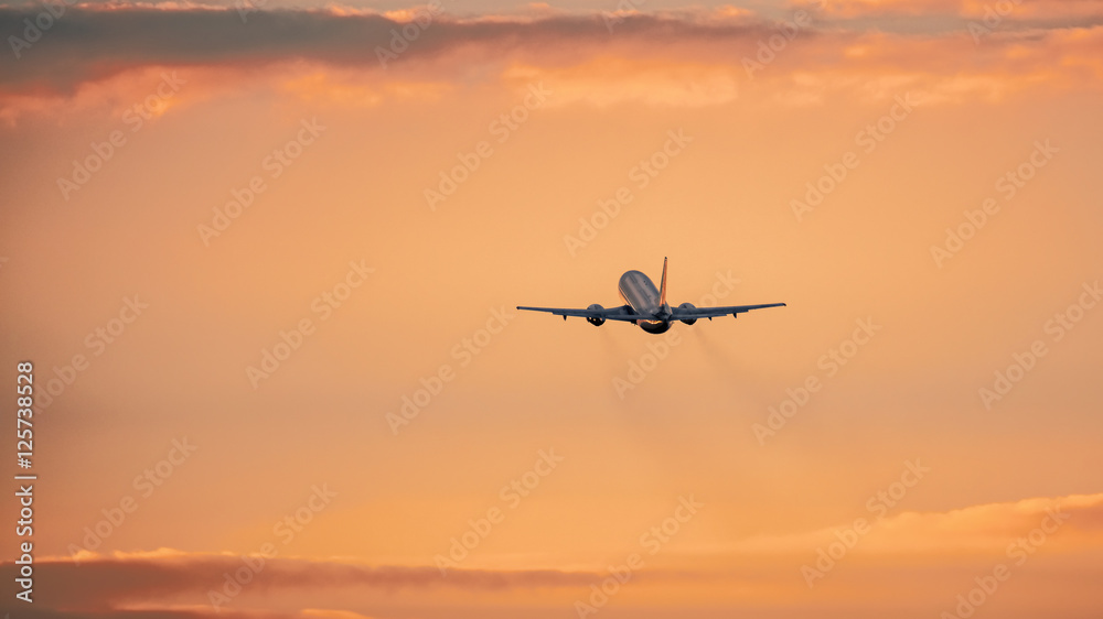 Airplane in the air and sunset in background