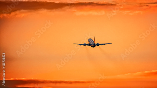 Airplane in the air and sunset in background © Baranov