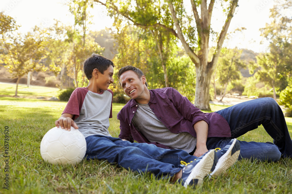 Father and son relaxing with soccer ball in a park, close up Father and son relaxing with soccer ball in a park, close up